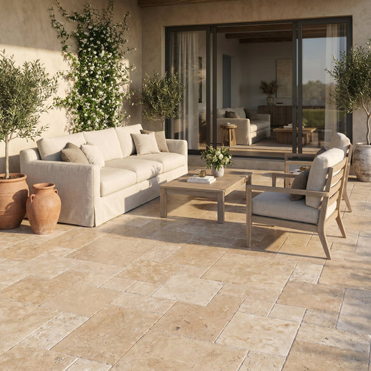 Outdoor patio with beige sofa, wooden coffee table, and chairs on a stone patio. Aspendos Tumbled Travertine Pavers