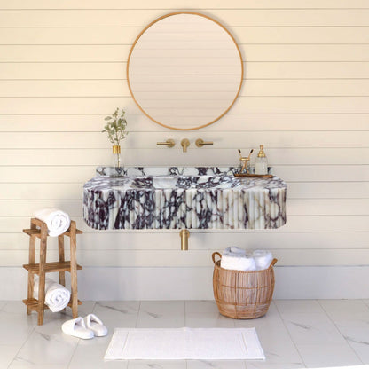 Calacatta Viola Marble Wall-mount Bathroom Vanity Ribbed Textured Front (W)18" (L)32" installed bright bathroom round gold frame mirror soap dispenser glass vase and plant gold wall-mount faucet towel box side wooden table shelf white foot towel 