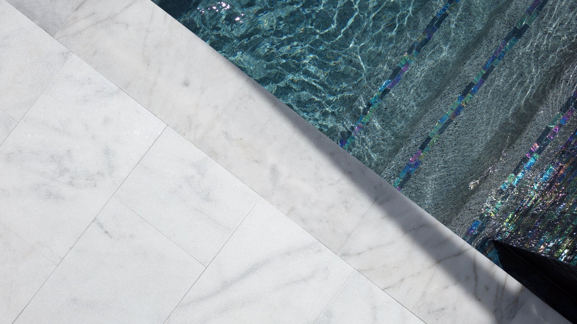 Close-up of a white marble ledge with water reflections.
