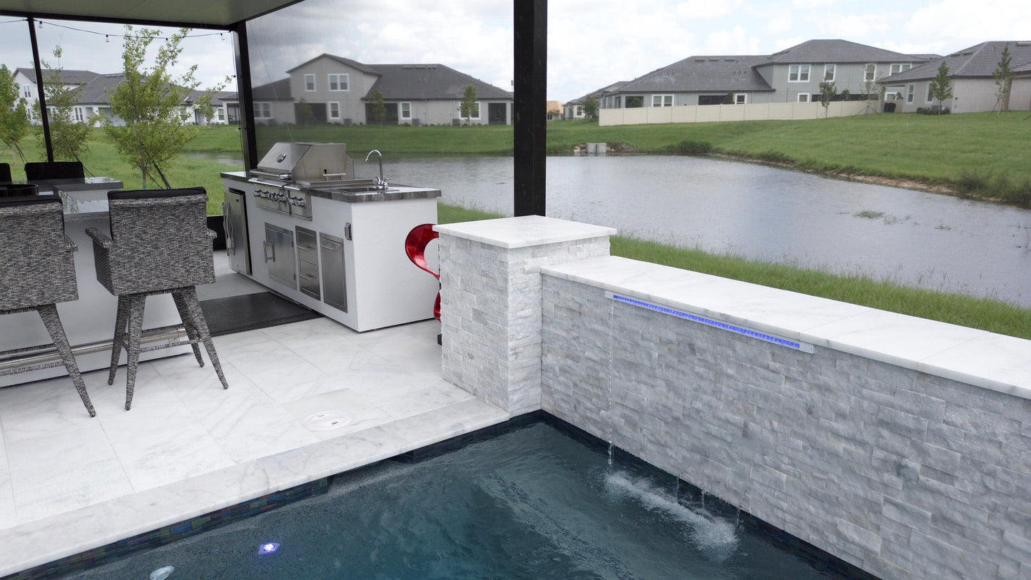Outdoor kitchen with pool and residential area view. Turkish Carrara White Marble Sand-Blasted Pavers