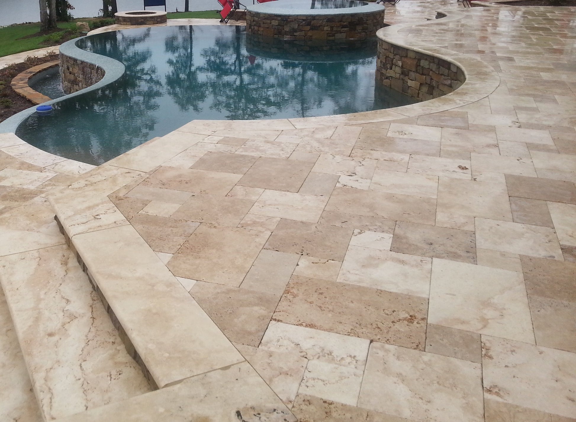Beige stone patio with a pool in the background Aspendos Tumbled Travertine Pavers