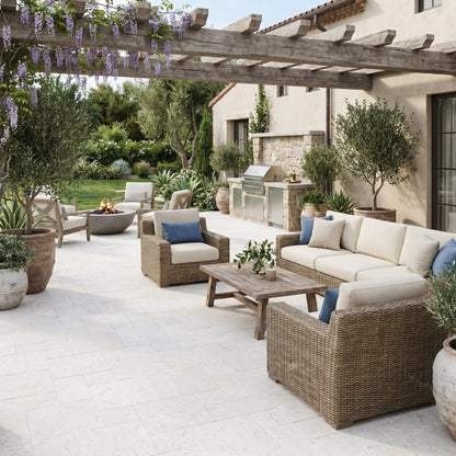 Outdoor patio with wicker furniture, pergola, and potted plants Shell Stone White Tumbled Limestone Pavers