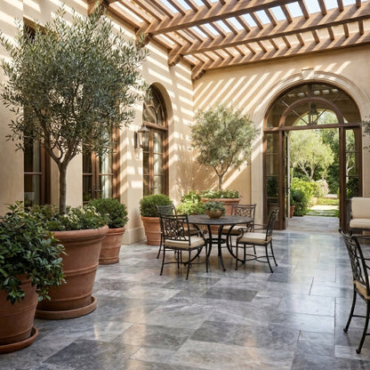 Outdoor patio area with tables, chairs, and potted plants under a pergola. Silver Shadow Marble Tumbled Pavers (3cm Thickness)