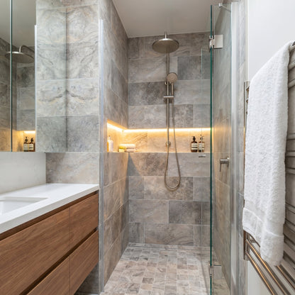 Modern bathroom with shower area, wooden vanity, and towel rack.