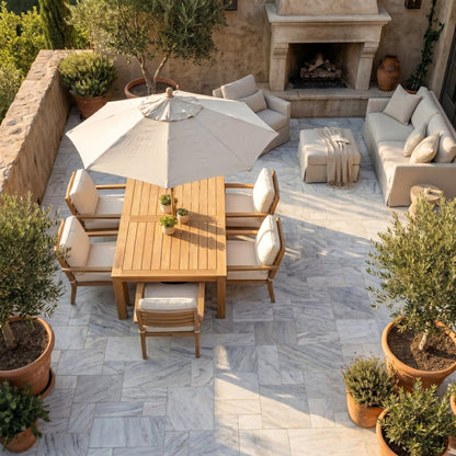 Outdoor patio with wooden table, chairs, and umbrella on a stone patio. Solto White Marble Leathered Pavers